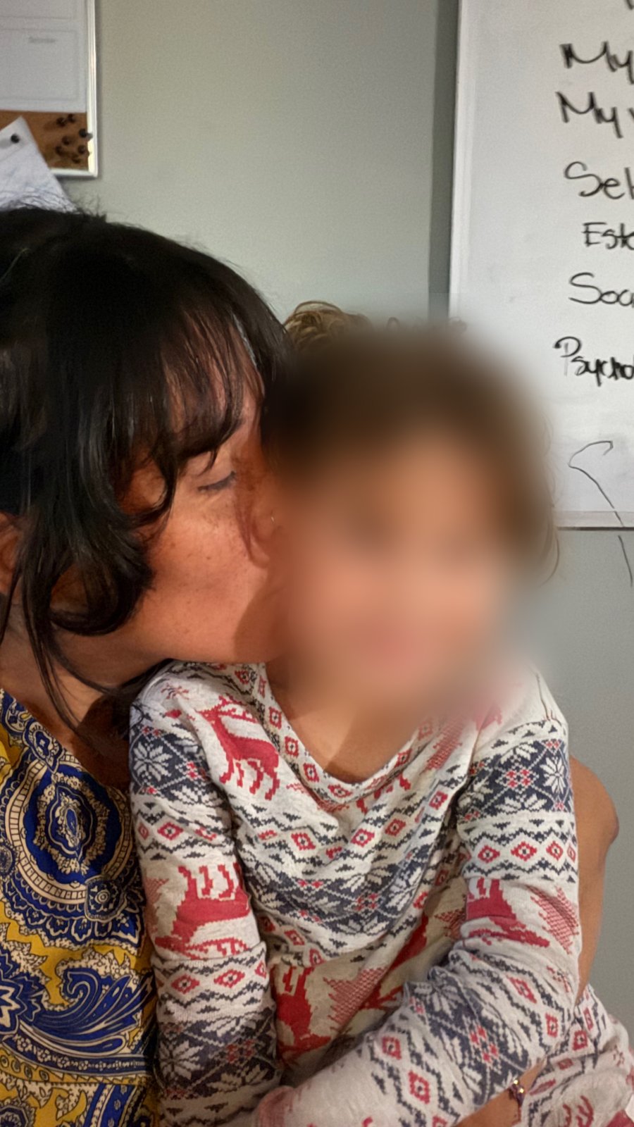 Paola Andrea kissing her young daughter on the cheek.