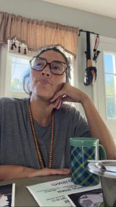 Paola Andrea at her kitchen table with a cup of tea, resting her chin on her hand.