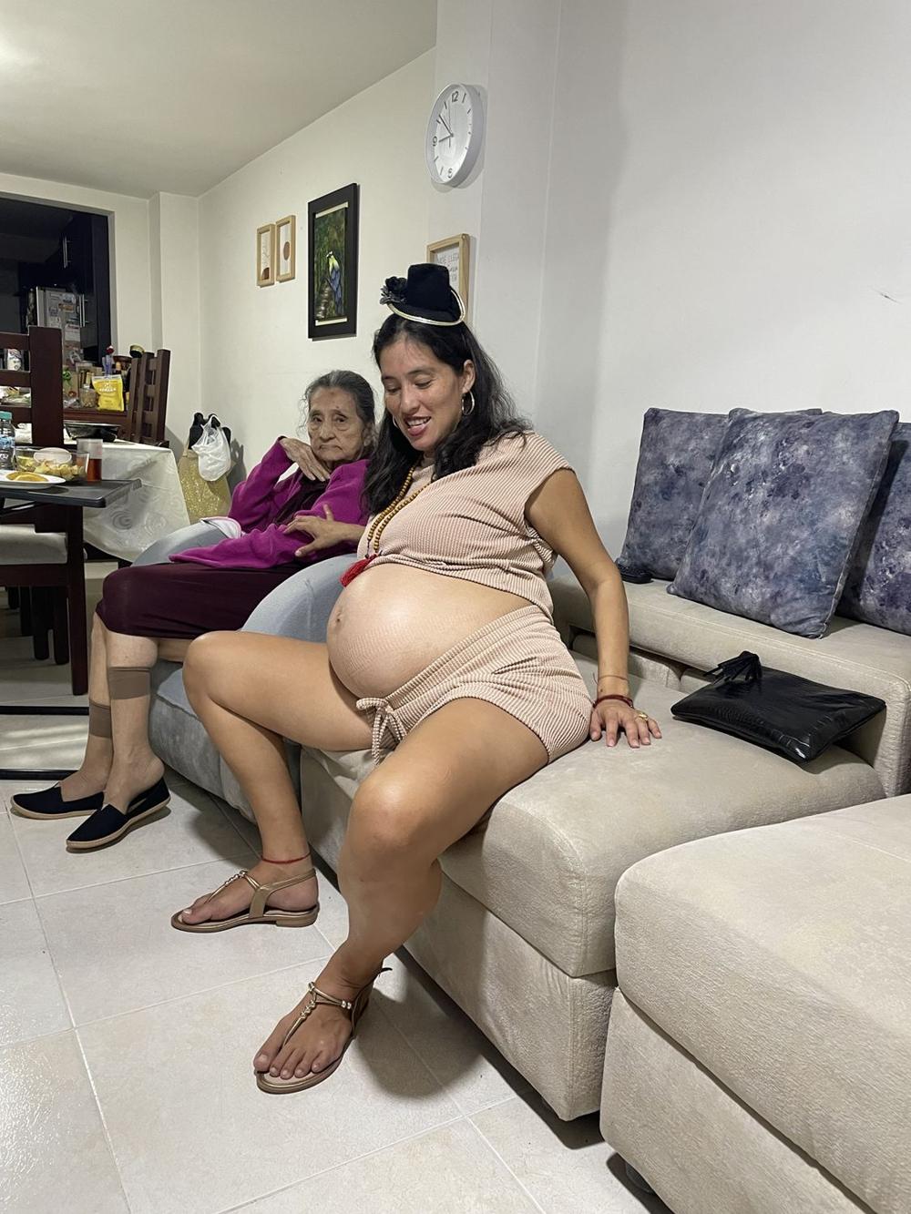 Paola Andrea, pregnant, sitting on the couch beside an elder woman of her family in Colombia.
